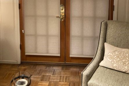 Cozy Mountain View living room corner showcasing grey armchair and high quality roller shades installed on patio doors.